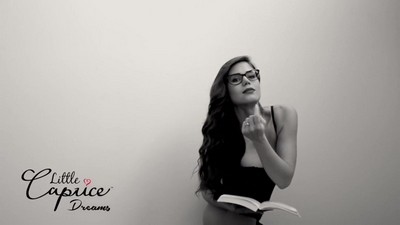 Little Caprice, wearing a gag, engages in anal play.